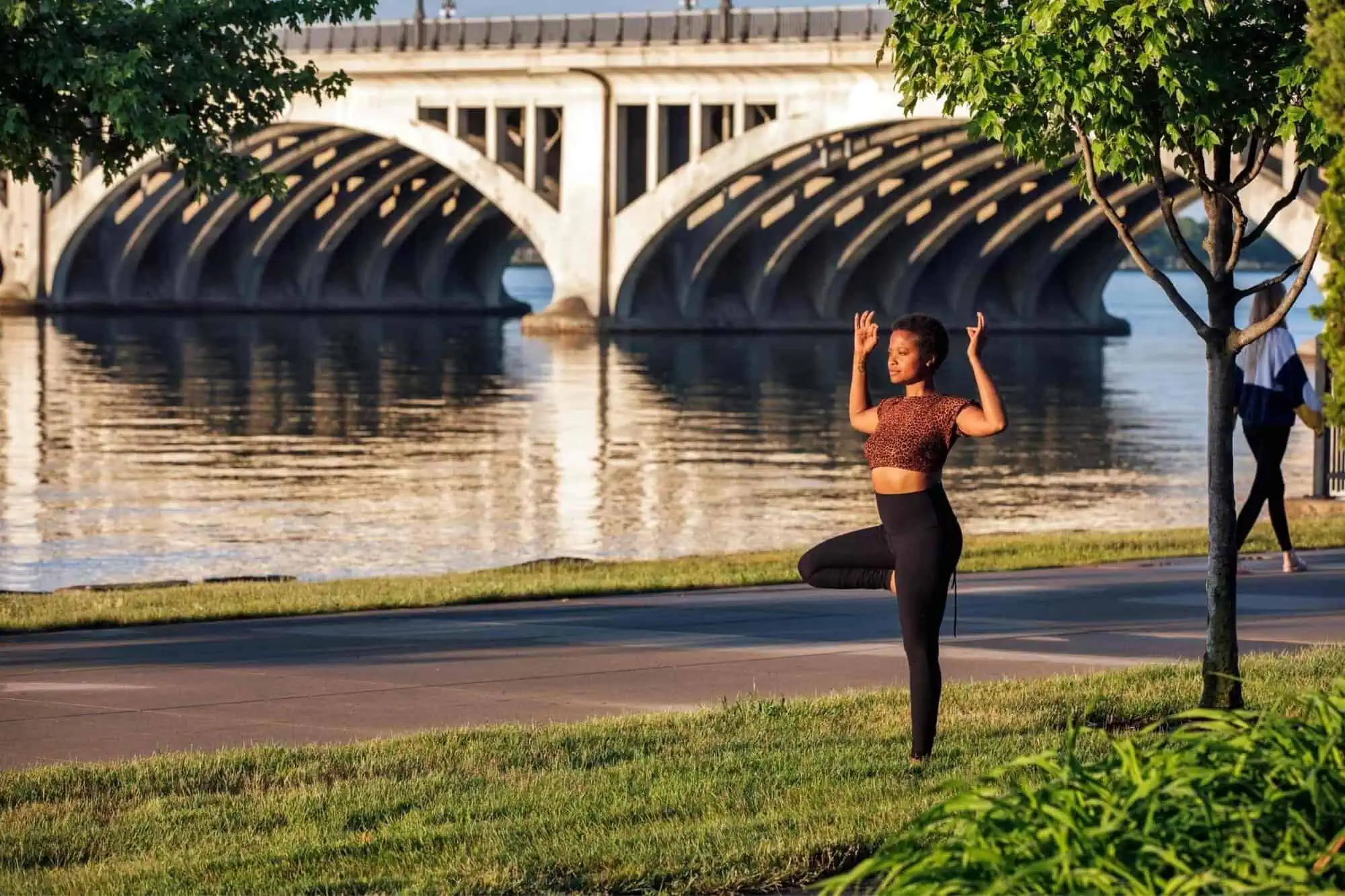 A woman practicing yoga near the shoreline in the early morning where the sun is rising